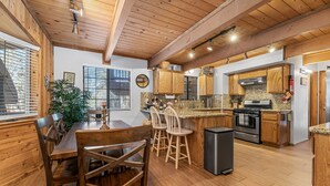 A kitchen with wooden cabinets, a granite countertop, and a black trash bin. - Walk to Bear Resort with Slope Views. Close to Zoo & Golf, Spa, BBQ & Arcade! (Big Bear Lake)