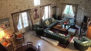 Un accogliente soggiorno con parete in pietra, divano, tavolino e zona pranzo con sedie e tavolo.