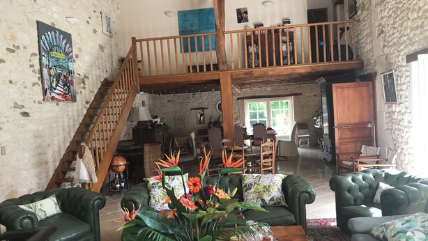 Un'ampia zona giorno con soffitto alto, una scala in legno e una sala da pranzo.