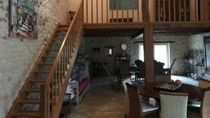 Un ambiente rustico con una scala in legno, un'area da pranzo con una scacchiera e un soppalco.