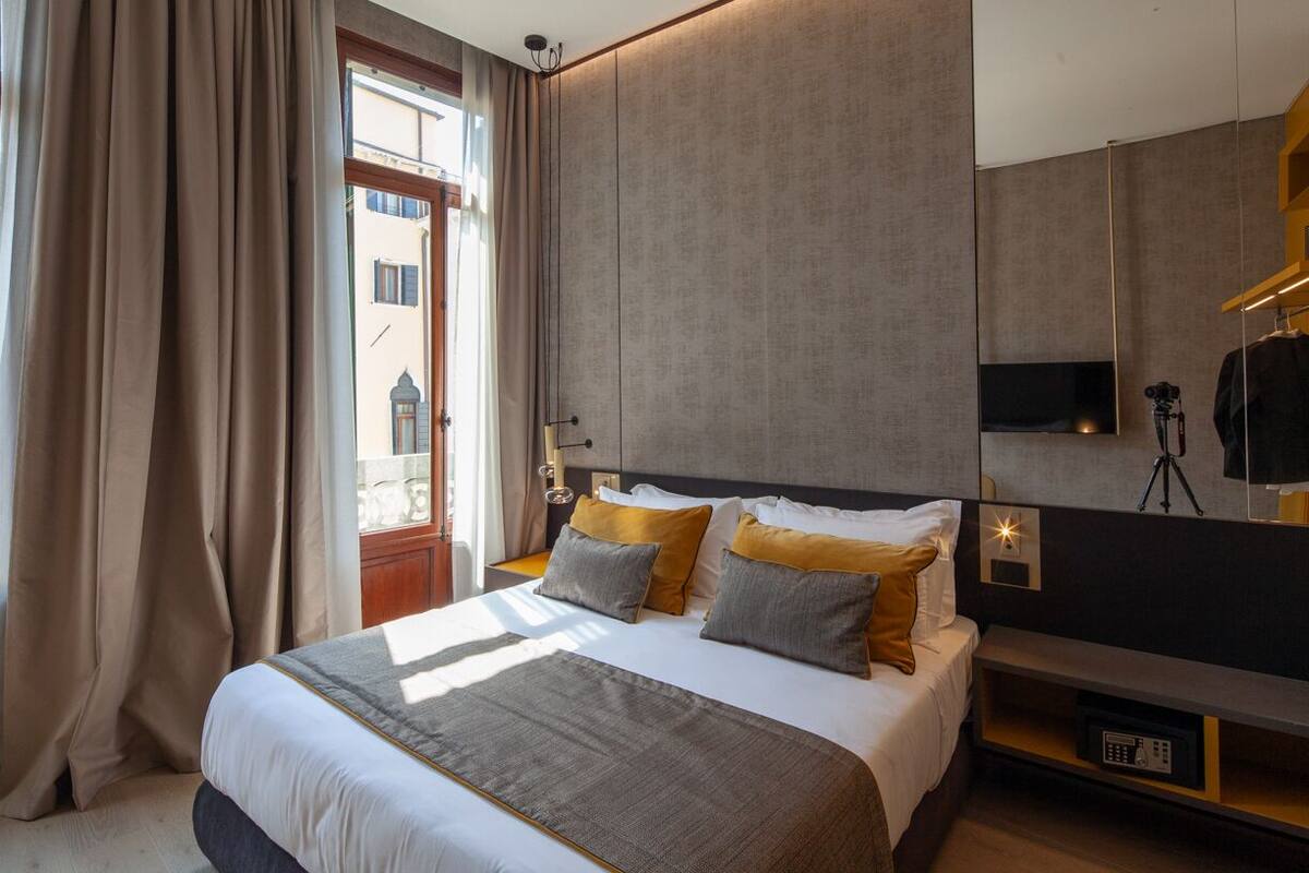 A modern hotel room with a large bed, a TV, and a mirror.
