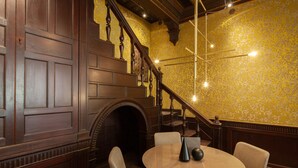 A room with a wooden staircase, a fireplace, and a round table with chairs. - Palazzo Pianca (Venice)