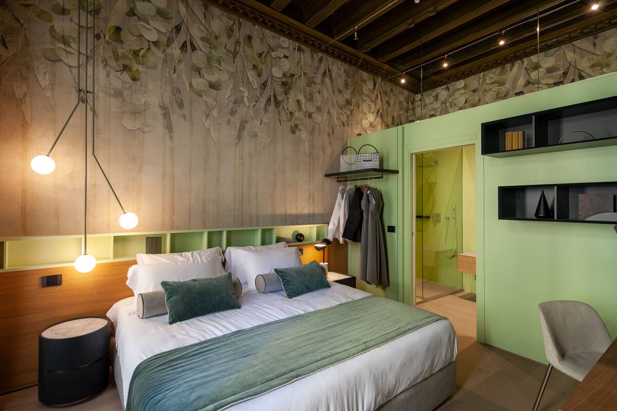 A modern bedroom with a large bed, bedside tables, a chair, and a wardrobe.