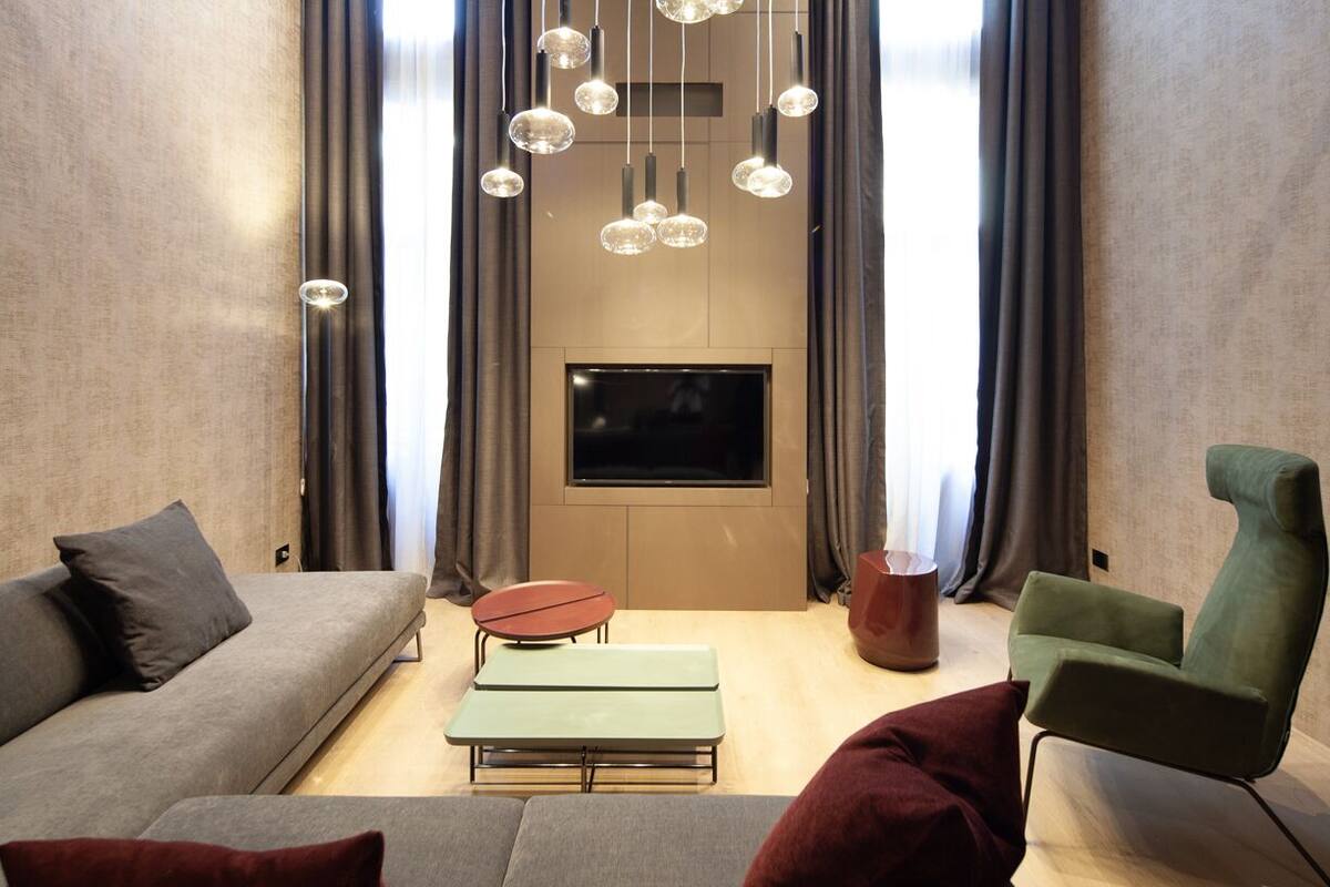 A modern living room with a sofa, a green armchair, a small table, and a bench.