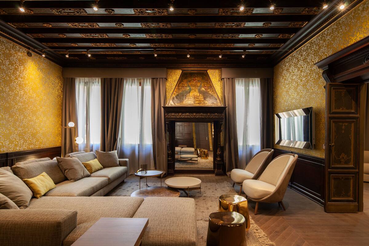 A luxurious living room with a sofa, armchairs, a coffee table, and a fireplace.