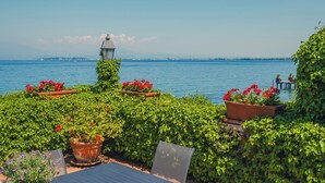 Eine Uferterrasse mit Topfpflanzen, einem Laternenlicht und Blick auf das Meer.