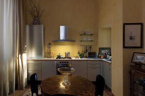 A kitchen with a stove, oven, and microwave. There is a dining table with chairs and a vase on the counter.