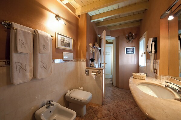 A bathroom with a sink, toilet, bidet, and towels with initials. - Domus Nova - Camera Regina Adelaide (Verona)