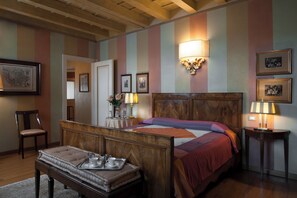 A hotel room with a wooden bed, a bedside table with a lamp, a chair, and a tray with a cup and saucer. - Domus Nova - Camera Regina Adelaide (Verona)