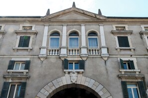 A historic building with a symmetrical facade, three arched windows, and a central balcony with balustrades.