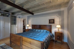 A bedroom with a wooden bed, two bedside tables with lamps, a wardrobe, and a framed picture on the wall.