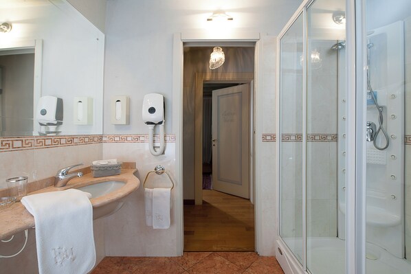 A bathroom with a sink, mirror, towel rack, and glass-enclosed shower.