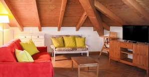Relax in this charming attic room with a sofa, coffee table, and TV.