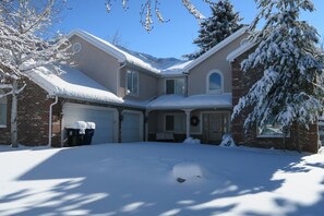 Two-story home with a symmetrical facade, featuring a brick and stucco exterior, and a small porch area.