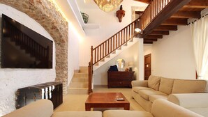 A living room with a stone wall, a wooden staircase, a sofa set, and a fireplace. - Ben Sa, Finca 5StarsHome Mallorca (Puerto Pollensa)