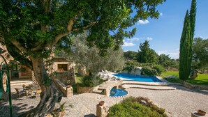 A stone patio with a swimming pool, lounge chairs, and a large tree. - Ben Sa, Finca 5StarsHome Mallorca (Puerto Pollensa)