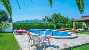 A swimming pool with lounge chairs and a table, surrounded by a stone patio and greenery, with mountains in the background. - Borges, 5StarsHome Mallorca Estate (Alcúdia)