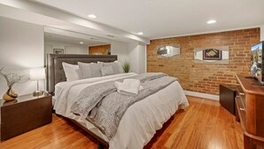 Une chambre moderne avec un grand lit, un mur décoratif en briques et un plancher en bois.