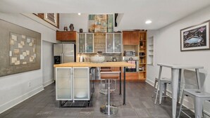 Une cuisine moderne dotée d’un îlot central, d’appareils électroménagers en acier inoxydable et d’un plan de travail en bois.