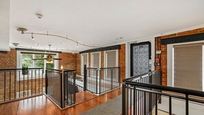 Un intérieur spacieux avec un plancher en bois, des rampes en métal et de grandes fenêtres.