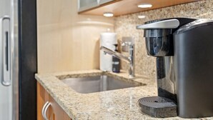 Une cuisine moderne dotée d’une machine à café intégrée, d’un évier en acier inoxydable et de plans de travail en granit.