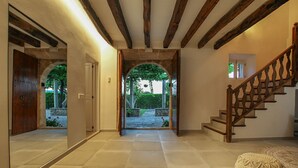 A hallway with a wooden staircase, a stone archway, and a view of a garden. - Vivamont, Villa-Finca 5StarsHome Mallorca (Pollensa / Pollença)