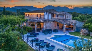 A two-story stone house with a swimming pool, outdoor seating, and a view of mountains. - Vivamont, Villa-Finca 5StarsHome Mallorca (Pollensa / Pollença)