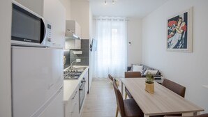 Cozinha moderna com micro-ondas, fogão e pia. Há uma área de jantar com mesa e cadeiras. Um quadro está na parede.