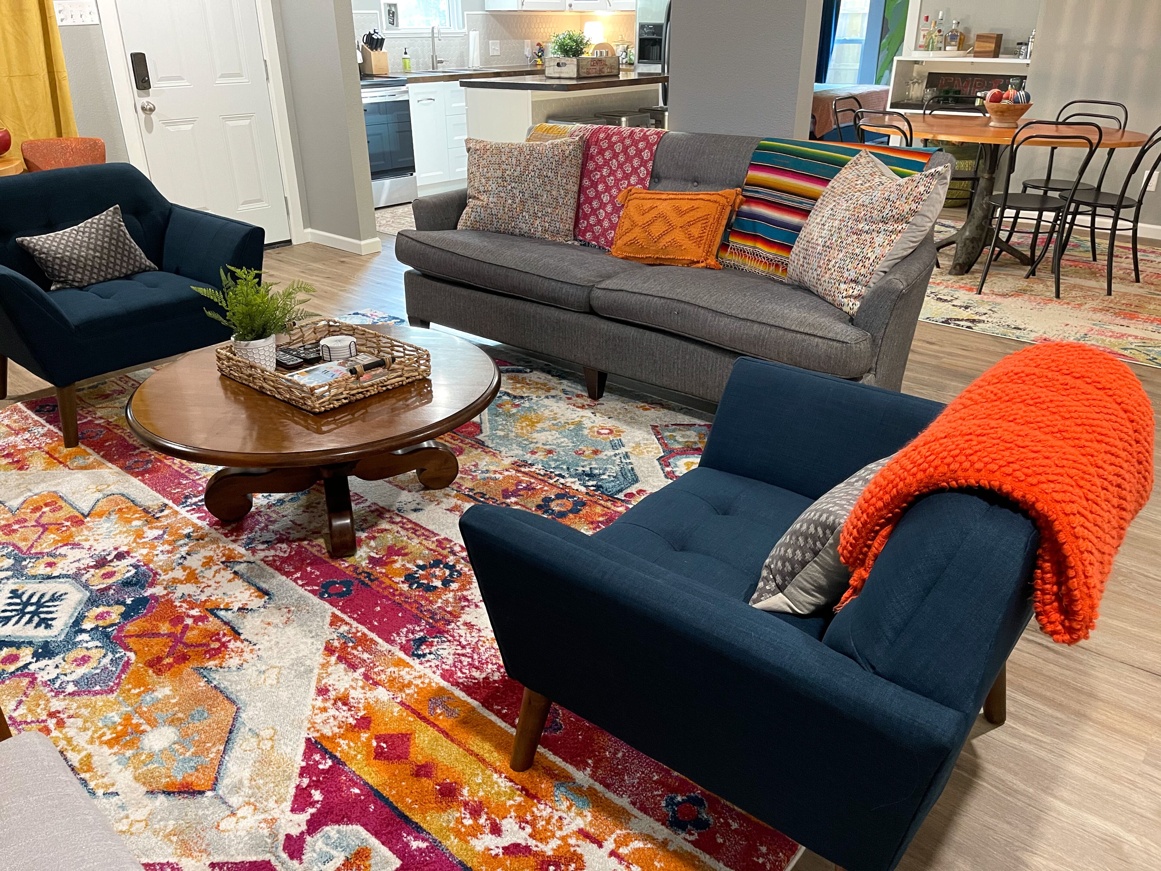 Een woonkamer met een bank, twee fauteuils, een salontafel en een kleurrijk tapijt.