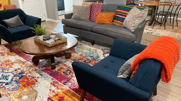 Een woonkamer met een bank, twee fauteuils, een salontafel en een kleurrijk tapijt.