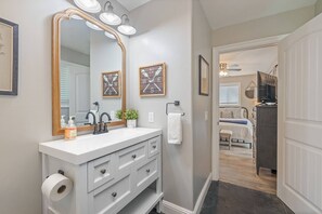 A bathroom with a vanity, a large mirror, and a towel rack.