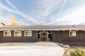 A single-story building with a dark exterior, a front door with a wreath, and a clear sky.