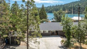 Une propriété résidentielle dotée d’un garage, d’un porche abrité et offrant une vue sur un lac et des collines boisées.