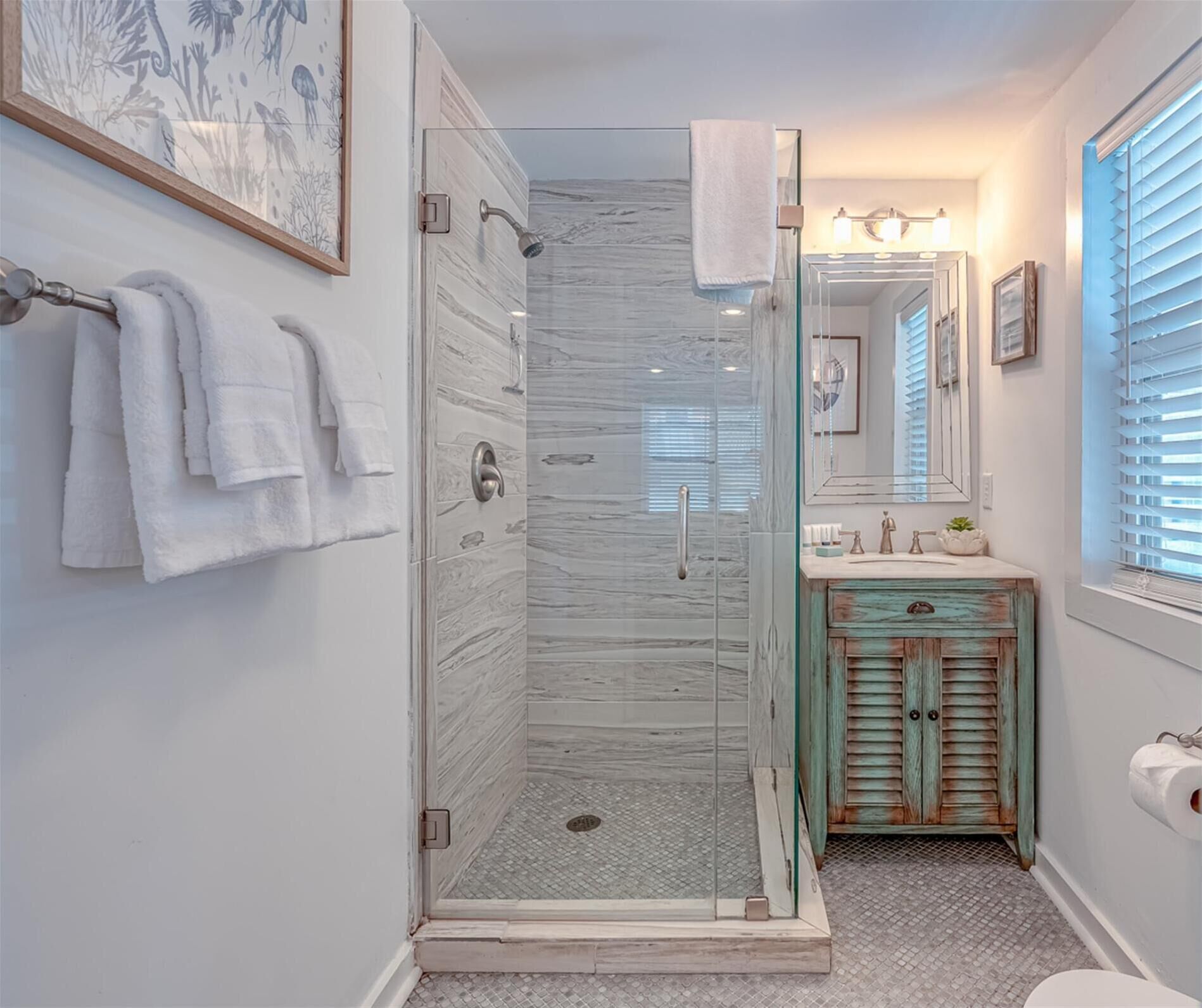 A bathroom with a glass-enclosed shower, a vanity with a rustic cabinet, and a large mirror above the sink.