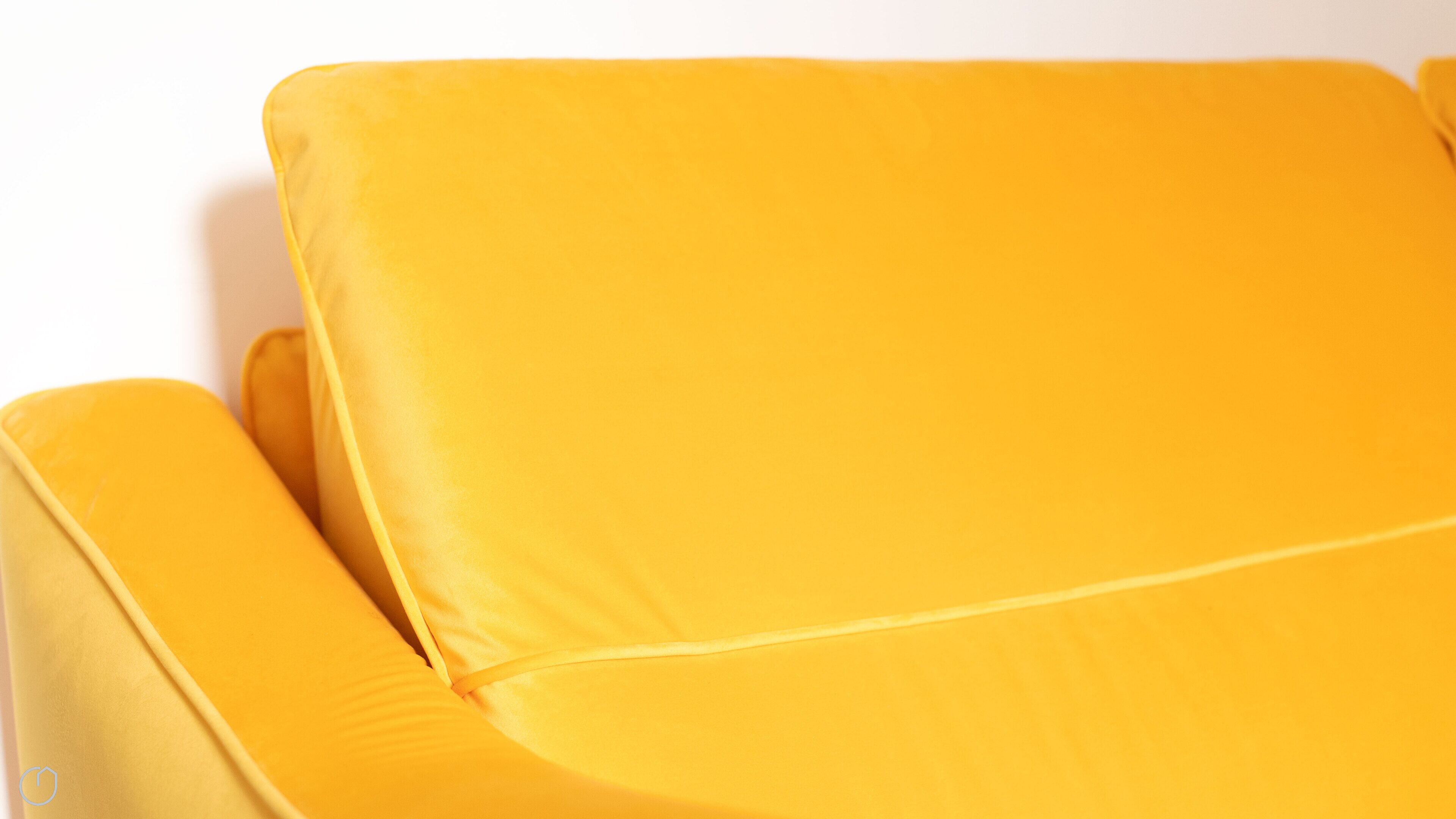 Primer plano de un sofá amarillo con un respaldo y reposabrazos acolchados y lisos.