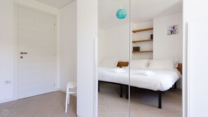 A bedroom with a bed, a chair, a shelf with books, and a door. - Villa Tola - Blu - One Bedroom Apartment, Sleeps 5 (Valdisotto)