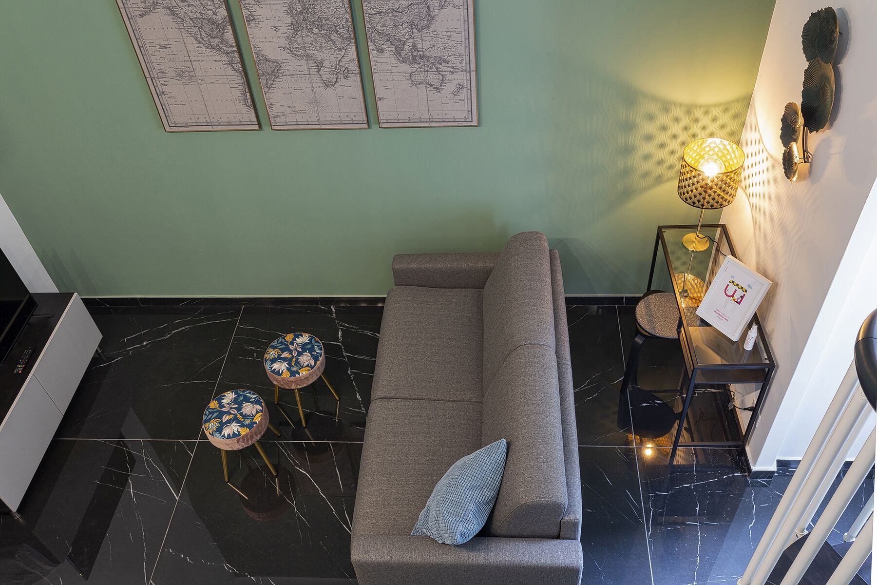 Ein modernes Wohnzimmer mit einem grauen Sofa, zwei runden Tischen mit floralem Muster und einer Wand-Globus.