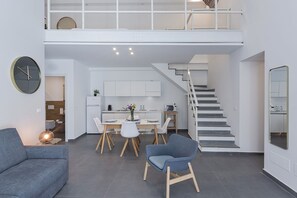 A modern apartment with a dining area, kitchen, and a staircase leading to an upper level. - Atelier Apartments by Wonderful Italy (Genoa)
