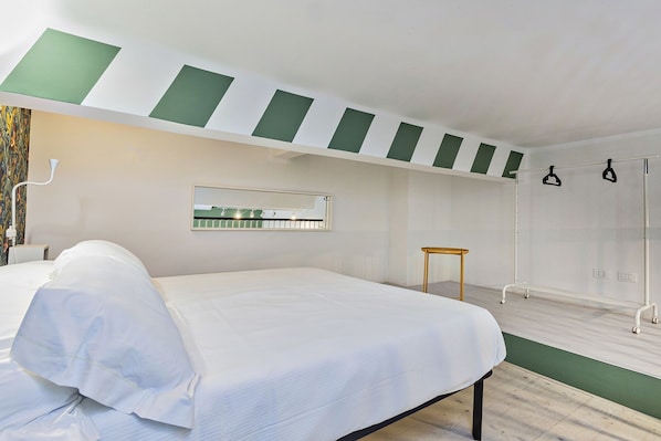 A hotel room with a bed, a small table, a mirror, and a shower area. - Atelier Apartments by Wonderful Italy (Genoa)