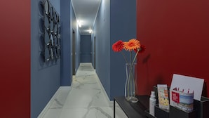 En hall med blå väggar, ett marmorgolv och en svart receptionsdisk med en vas med blommor och broschyrer.