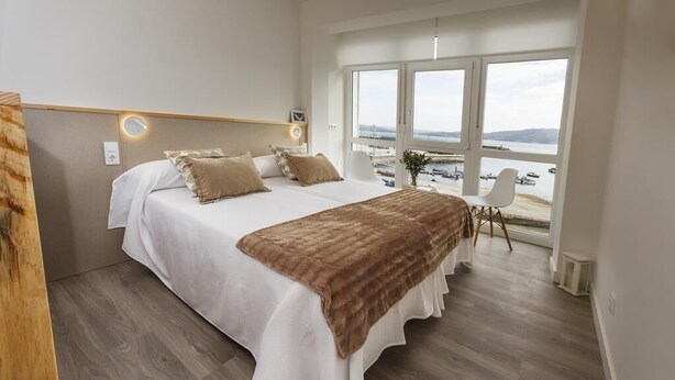 Une chambre avec un grand lit, une vue sur la mer et un plancher en bois.