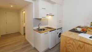 Une cuisine compacte équipée d’un évier, d’un lave-linge et d’un plan de travail en bois.