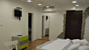 A bedroom with a bed, a desk, a chair, a dresser, and a mirror.
