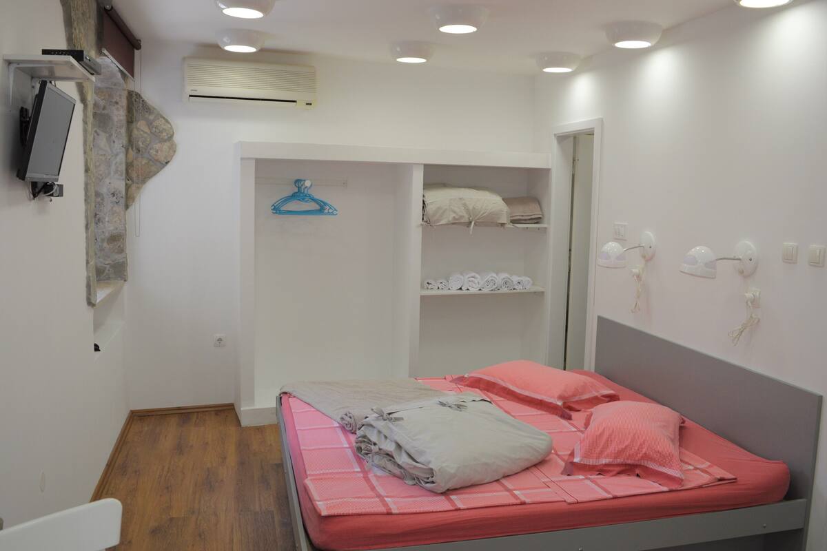 A bedroom with a bed, a wardrobe, a mirror, and a wall-mounted heater.