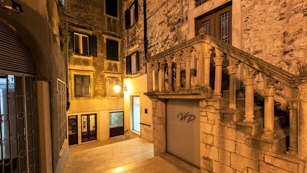 A narrow alleyway with a stone staircase leading to a building with a 'VP' sign.