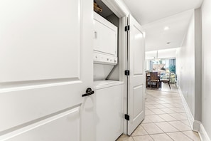 A hallway with a white door leading to a laundry area with a washing machine.
