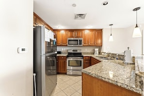 A kitchen with stainless steel appliances, wooden cabinets, granite countertops, and a built-in oven.