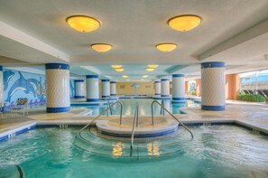 An indoor swimming pool with a central circular hot tub, surrounded by columns and a dolphin mural on the wall. - Mar Vista Grande 515-3BR/3BA Oceanfront condo in Ocean Dr. (North Myrtle Beach)