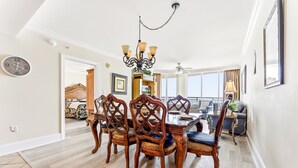 A dining area with a wooden table and chairs, a chandelier, and a clock on the wall.