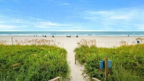 A beach path leading to the ocean with a clear sky.